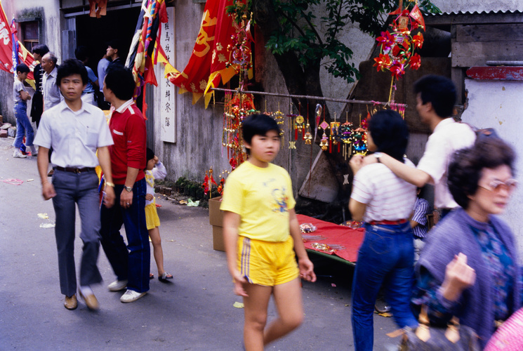 People, wind chimes and paper windmills on a street in Stanley