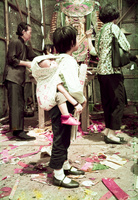 A girl carrying a baby in a traditional carrier [孭帶] with a word "Happiness 囍"